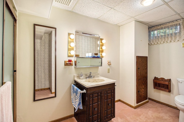 bathroom with a paneled ceiling, vanity, and toilet