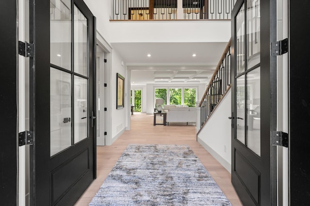 entryway with coffered ceiling, light hardwood / wood-style floors, and beamed ceiling