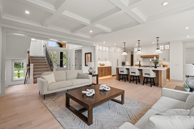 living room featuring coffered ceiling, beam ceiling, ornamental molding, and light hardwood / wood-style floors