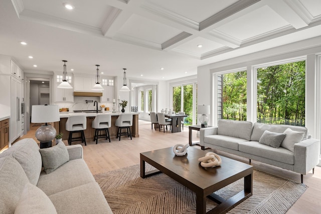 living room featuring beamed ceiling, ornamental molding, coffered ceiling, and light wood-type flooring