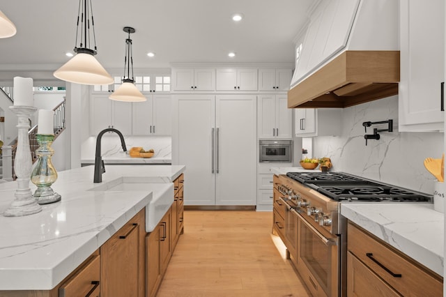 kitchen featuring premium appliances, sink, custom exhaust hood, and white cabinets