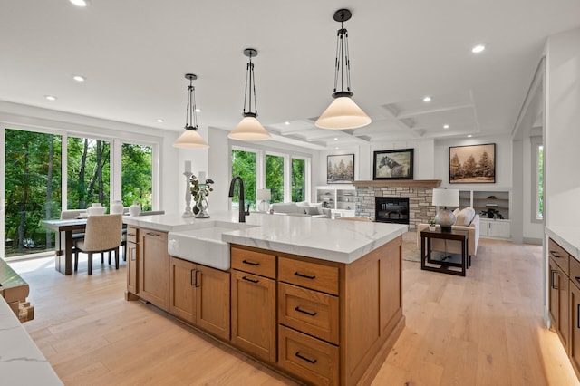 kitchen with decorative light fixtures, light stone countertops, and a large island with sink