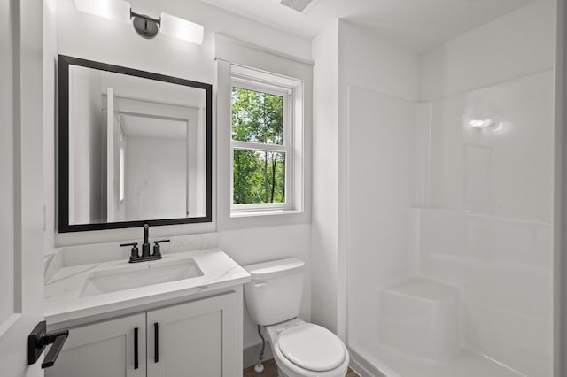 bathroom with toilet, vanity, and walk in shower