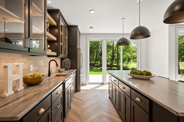 kitchen with a wealth of natural light, stainless steel refrigerator, sink, backsplash, and light parquet floors