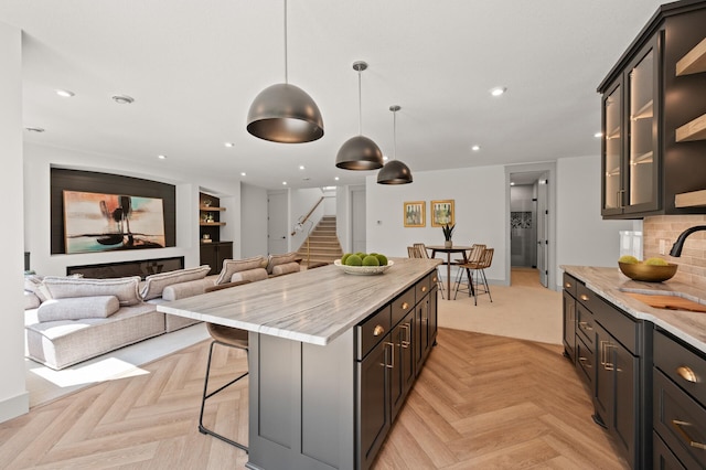 kitchen with decorative light fixtures, light stone countertops, light parquet flooring, and a kitchen island