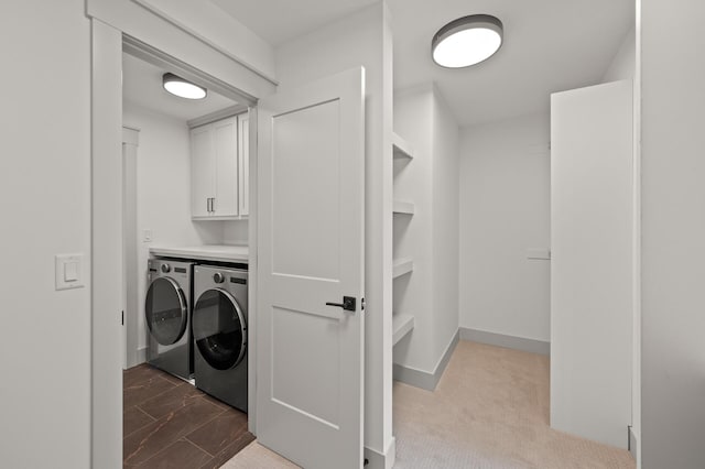 clothes washing area featuring washing machine and dryer and cabinets