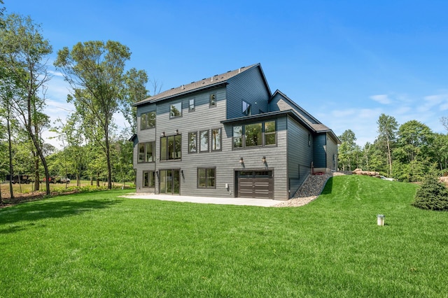 rear view of property with a garage, a yard, and a patio area