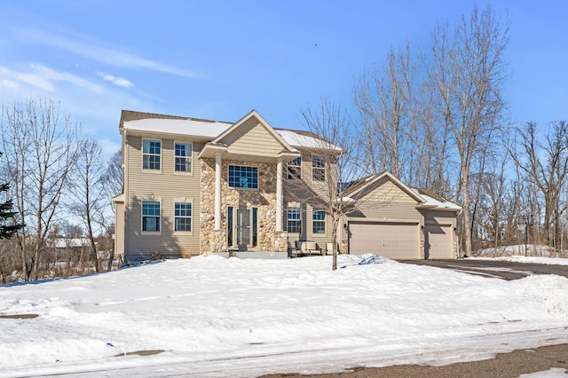 greek revival inspired property with an attached garage and stone siding