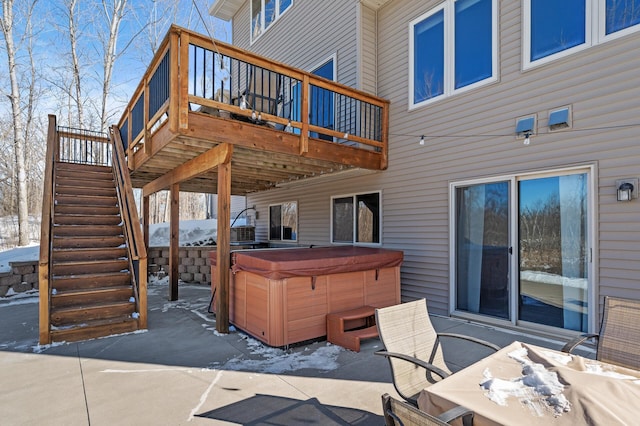 snow covered patio featuring stairs, a wooden deck, and a hot tub