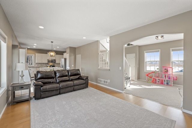 living room featuring recessed lighting, visible vents, stairway, light wood-type flooring, and baseboards