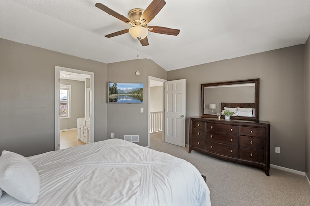 bedroom featuring ensuite bathroom, light colored carpet, visible vents, baseboards, and vaulted ceiling