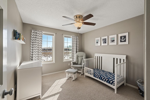 bedroom with a nursery area, ceiling fan, carpet flooring, and baseboards