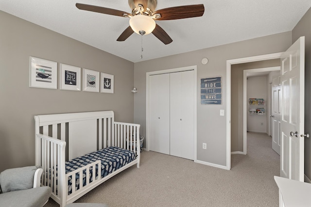 bedroom with ceiling fan, carpet floors, baseboards, a closet, and a crib