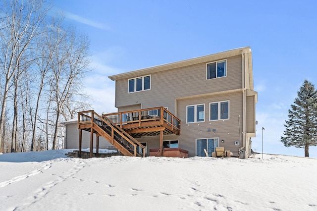 snow covered back of property with a deck and stairs