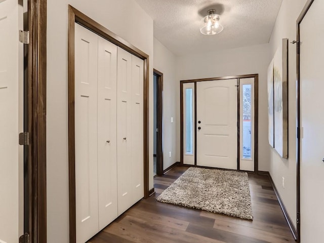 foyer entrance featuring dark wood-type flooring and a textured ceiling