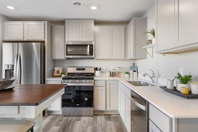 kitchen with white cabinets, appliances with stainless steel finishes, sink, and light wood-type flooring