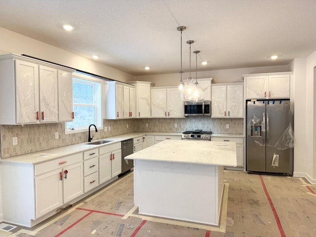 kitchen with appliances with stainless steel finishes, decorative light fixtures, white cabinetry, sink, and a center island