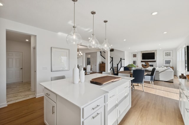 kitchen with white cabinetry, a kitchen island, hanging light fixtures, and light hardwood / wood-style flooring