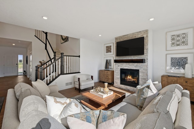 living room with dark hardwood / wood-style flooring and a stone fireplace