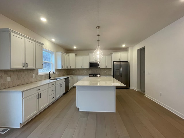 kitchen featuring hanging light fixtures, appliances with stainless steel finishes, a center island, and white cabinets