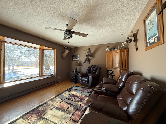 living room with wood-type flooring, a baseboard heating unit, a textured ceiling, and ceiling fan