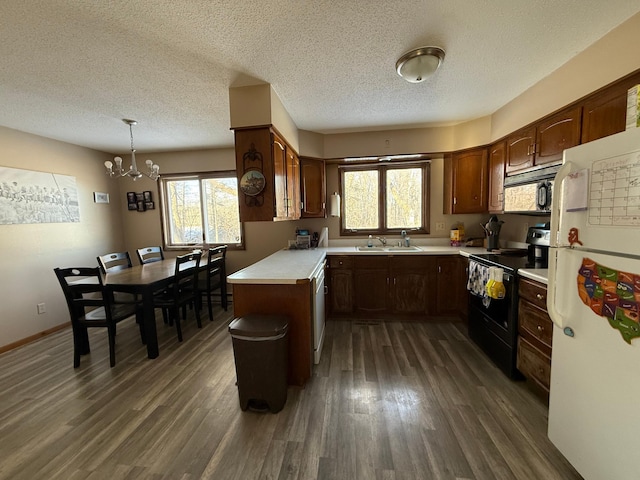 kitchen featuring hanging light fixtures, dark wood-type flooring, black appliances, and kitchen peninsula