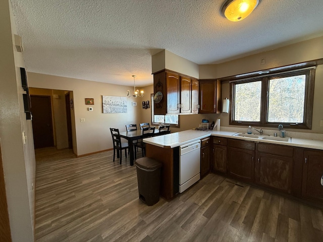 kitchen featuring sink, hanging light fixtures, dark hardwood / wood-style flooring, white dishwasher, and kitchen peninsula