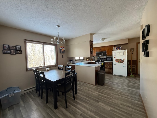 dining room with dark wood-type flooring, a chandelier, a textured ceiling, and a baseboard heating unit