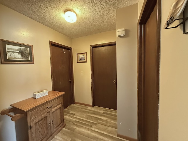 hallway with light hardwood / wood-style flooring and a textured ceiling