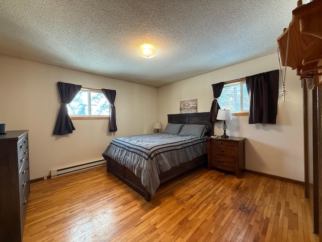 bedroom featuring a baseboard heating unit, a textured ceiling, and light hardwood / wood-style flooring