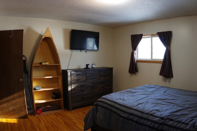 bedroom with light hardwood / wood-style floors and a textured ceiling