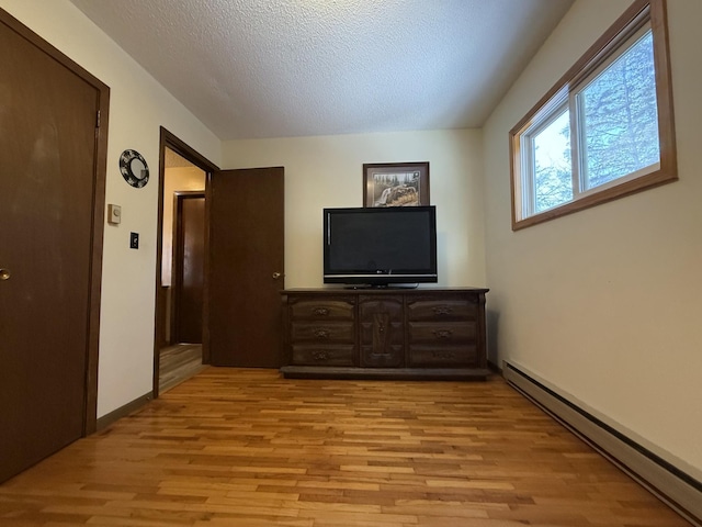 living room with a baseboard radiator, light hardwood / wood-style floors, and a textured ceiling