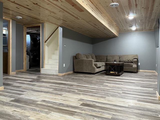 living room featuring wood ceiling, stacked washer / dryer, and light hardwood / wood-style floors