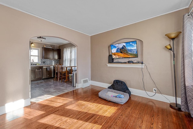 unfurnished room with ornamental molding, sink, and wood-type flooring