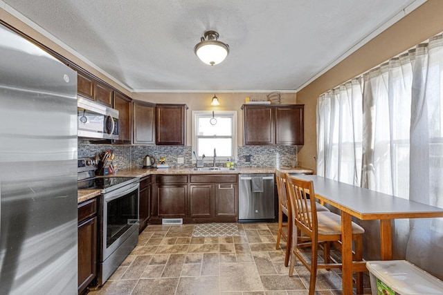 kitchen with dark brown cabinetry, sink, appliances with stainless steel finishes, ornamental molding, and decorative backsplash