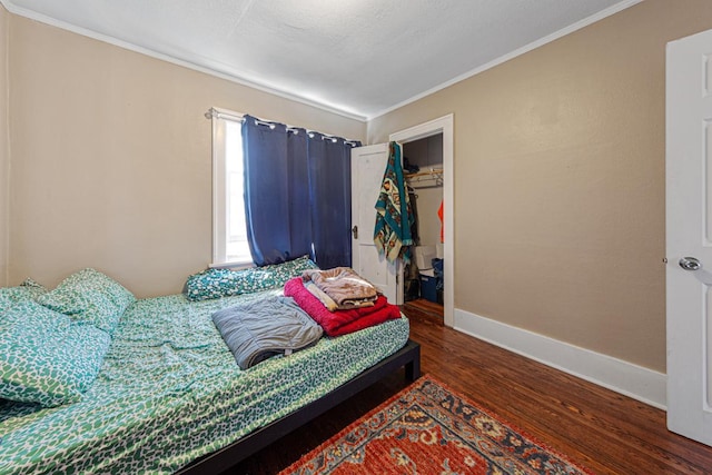 bedroom with a spacious closet, dark wood-type flooring, ornamental molding, and a closet