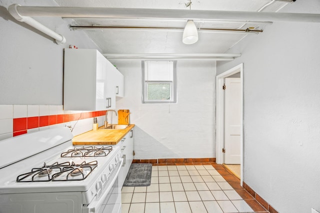 kitchen with light tile patterned flooring, sink, white gas stove, and white cabinets