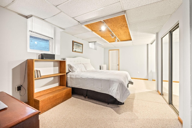 carpeted bedroom featuring a drop ceiling, radiator heating unit, and rail lighting