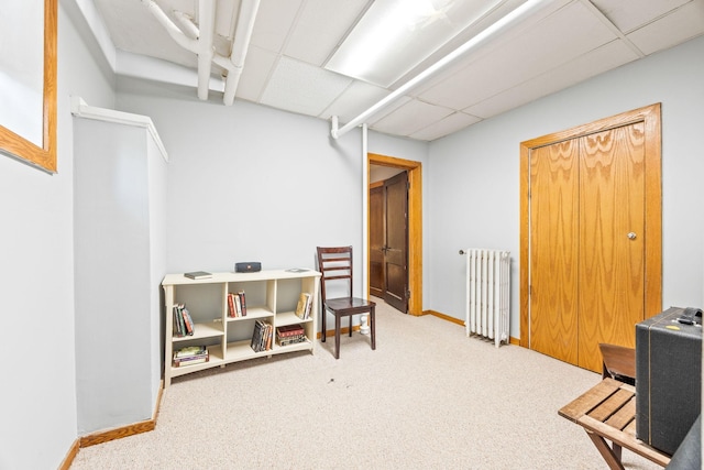 interior space featuring light carpet, radiator, and a paneled ceiling