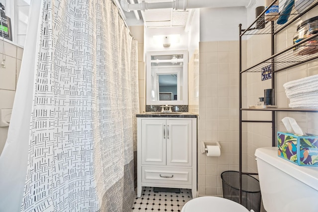 bathroom with tile walls, vanity, toilet, and a shower with shower curtain