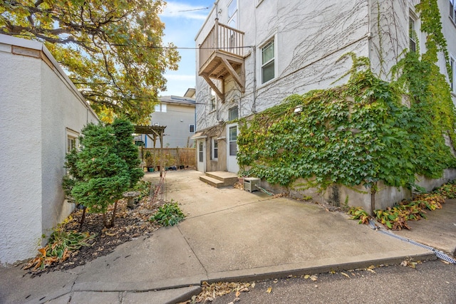 exterior space with stucco siding, a patio, a balcony, and a pergola