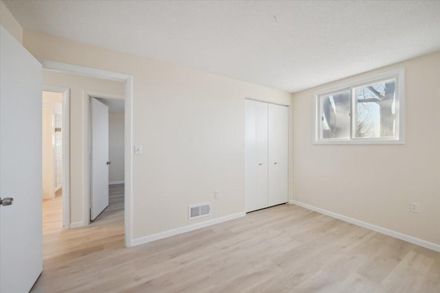 unfurnished bedroom featuring light hardwood / wood-style floors and a closet