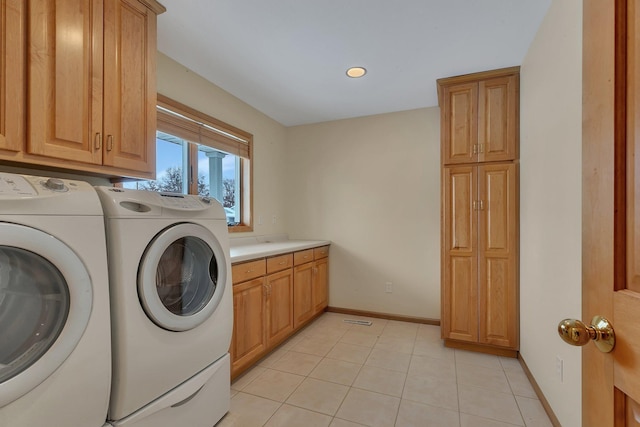 laundry room featuring light tile patterned floors, cabinets, and washing machine and clothes dryer