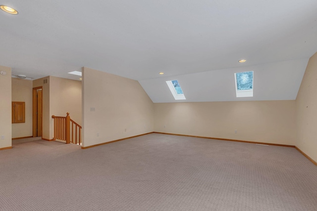 additional living space with lofted ceiling with skylight and light carpet