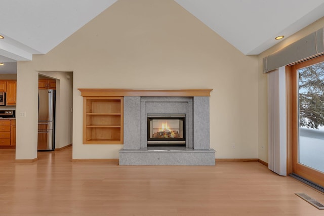 unfurnished living room with high vaulted ceiling, a high end fireplace, and light hardwood / wood-style floors