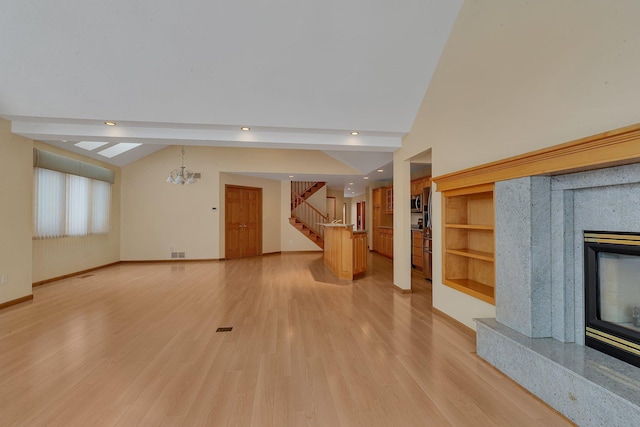 unfurnished living room featuring vaulted ceiling with beams, a notable chandelier, and light hardwood / wood-style floors