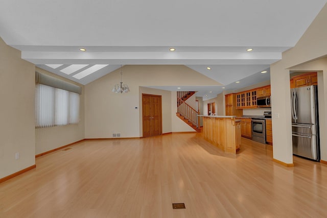 kitchen with a breakfast bar area, appliances with stainless steel finishes, a center island, lofted ceiling with beams, and light wood-type flooring