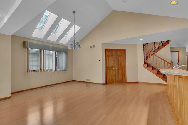 unfurnished living room featuring high vaulted ceiling, sink, a chandelier, and light hardwood / wood-style floors