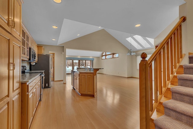 kitchen featuring decorative light fixtures, a kitchen breakfast bar, a kitchen island with sink, stainless steel appliances, and light wood-type flooring