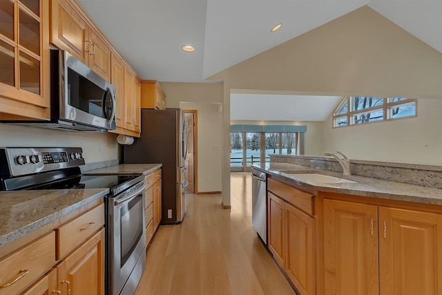 kitchen with light stone counters, stainless steel appliances, vaulted ceiling, and sink